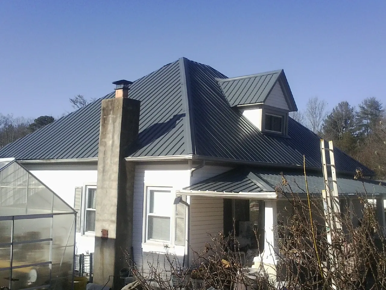 Dark blue standing seam metal roof on a white farmhouse with dormer — Slate & Tile Roof Repair by Roofing Brothers in Kutztown