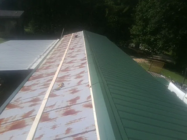 Old rusted panels beside newly installed green metal roofing — Wind Damage Roof Repair by Roofing Brothers in Kutztown