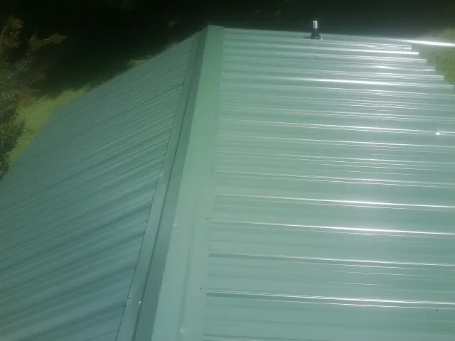 New green metal panels meeting at the ridge of a roof — Flat Roof Repair work by our crew in Kutztown