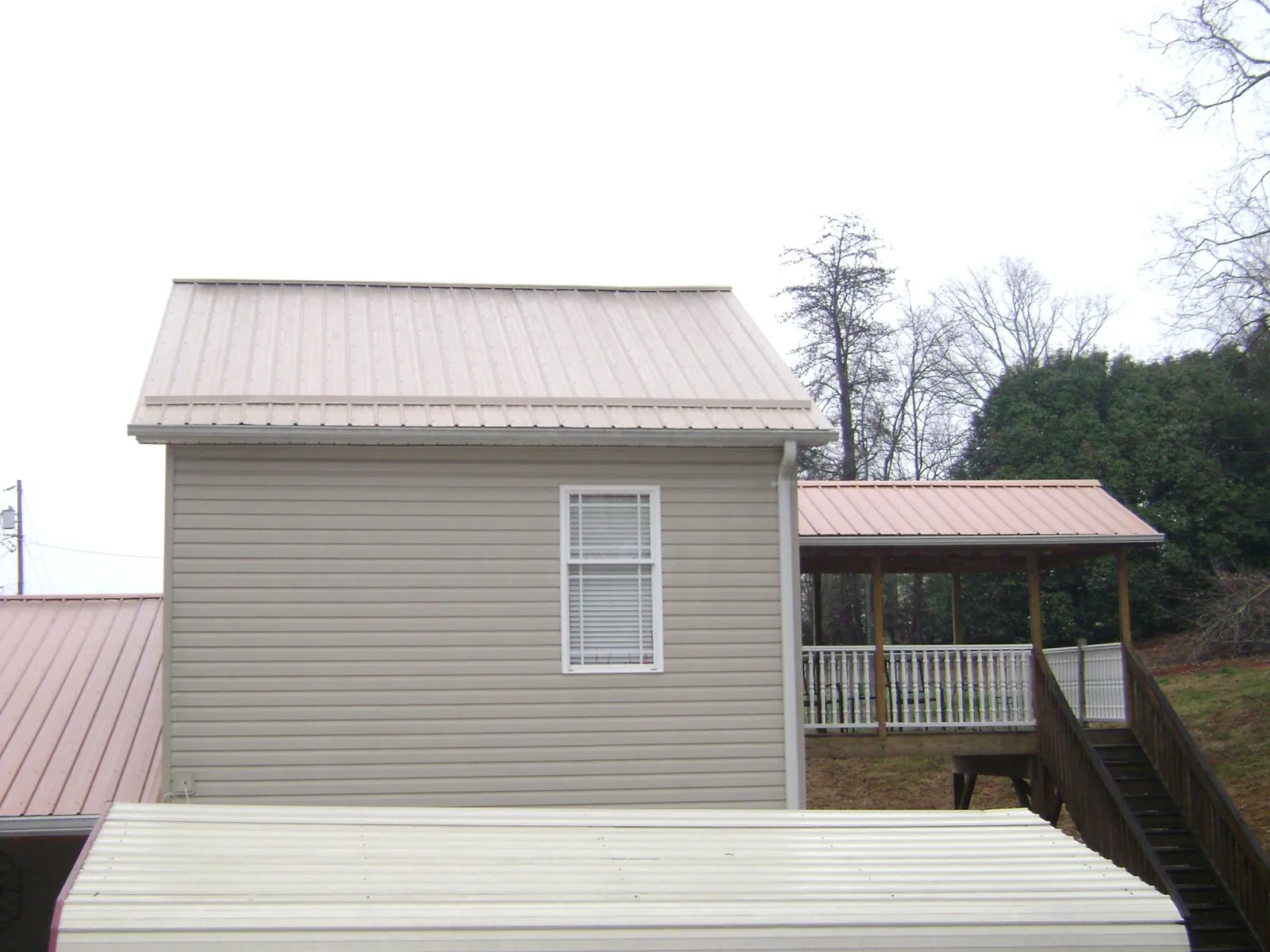 Tan metal roofs on a two story addition and attached porch, from a Roof Replacement job in Kutztown