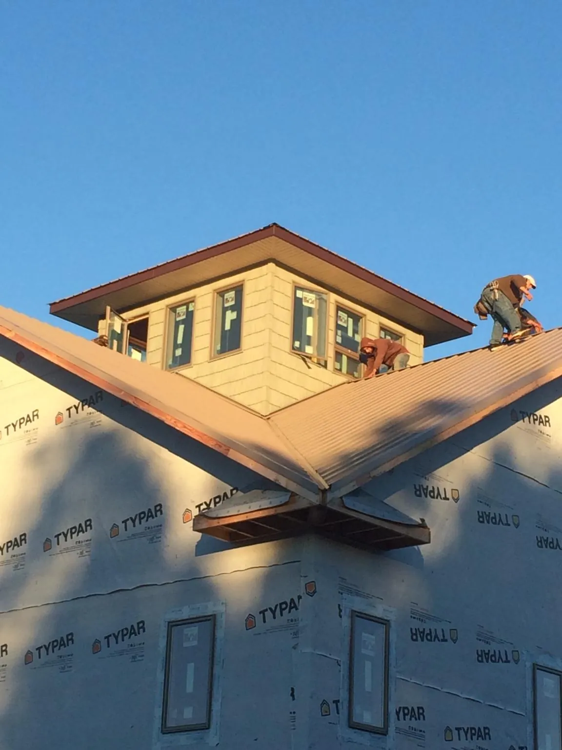 Roofers working around a rooftop cupola on a new metal roof at sunset — Roof Waterproofing in Kutztown by Roofing Brothers